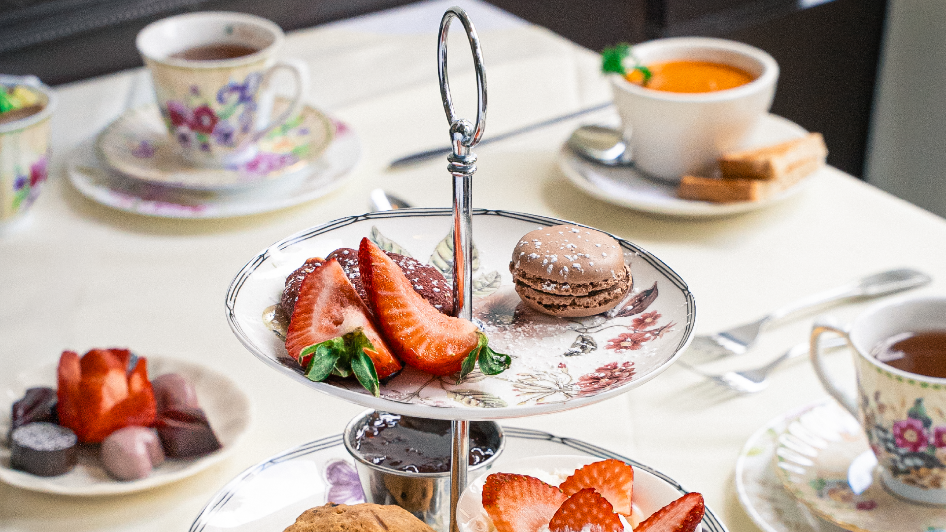 Chado Tea Room – tiered afternoon tea stand with scones, macarons and strawberries beside floral teacups.