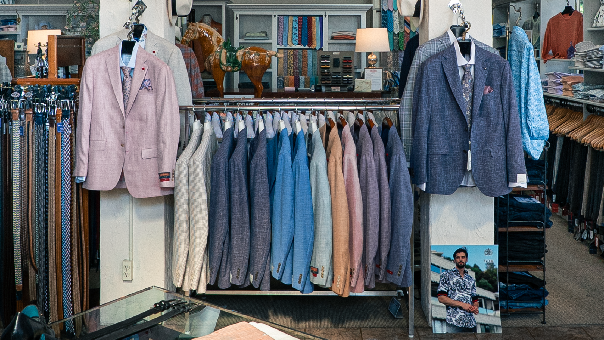 Mark Piscitelli Men's Fashions – racks of dress shirts, sport coats and suits displayed in the menswear shop.