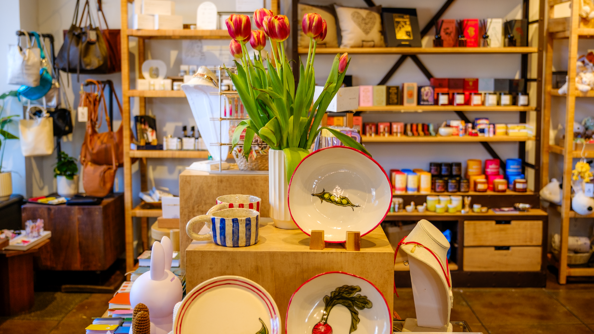 Homage Pasadena – display of handmade ceramic plates, mugs and home goods with a vase of tulips.