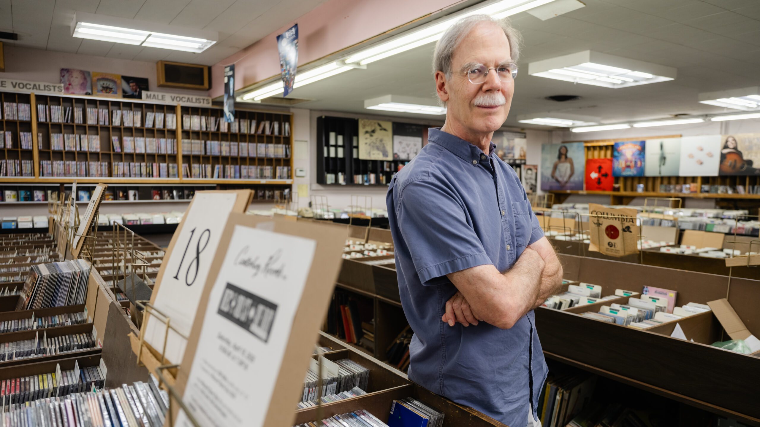 Canterbury Records – owner standing with arms crossed among the record bins and stacks of vinyl.