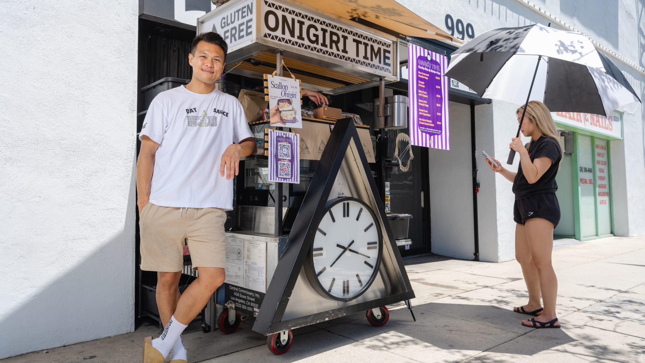 Onigiri Time – staff member outside the shop beside the A-frame sign for gluten-free onigiri rice balls.